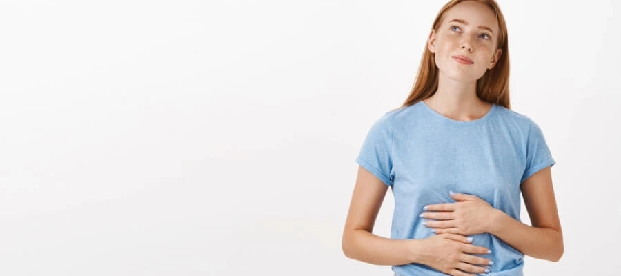 mulher jovem com as mãos na região da barriga e expressão e tranquilidade na face