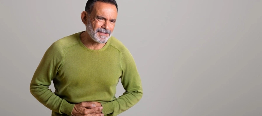 homem idoso com a mão na barriga sentindo dor