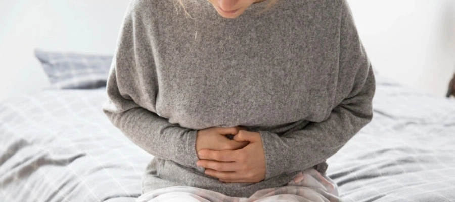 Mulher doente com as mãos no estômago, sofrendo de dor intensa