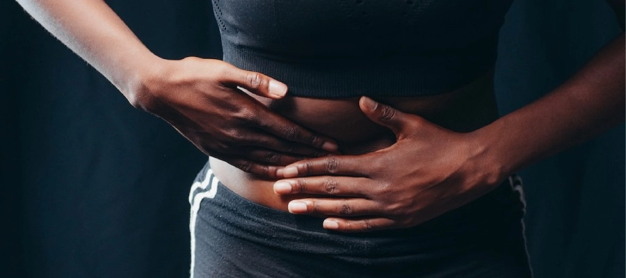 mulher negra massageia a barriga com as duas mãos