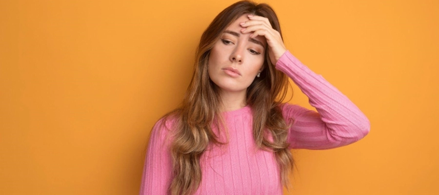uma mulher em um suéter rosa está segurando a cabeça
