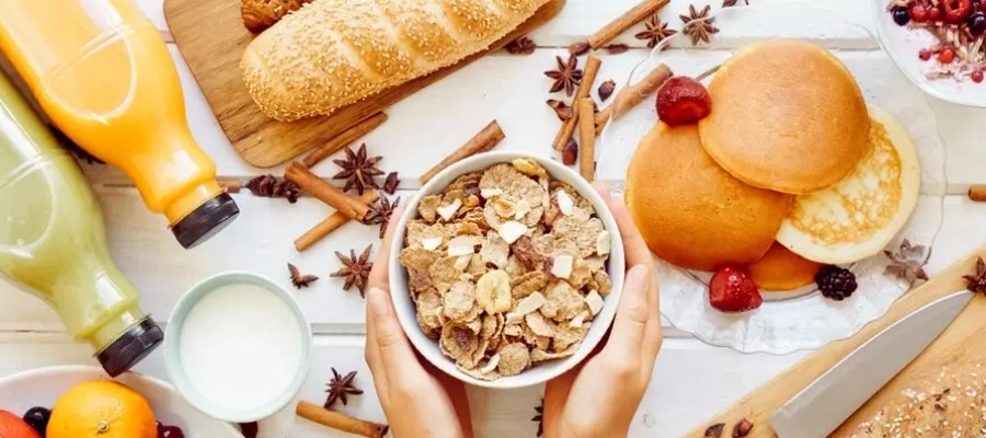 Foto superior de café da manhã saudável com mãos segurando bowl com cereais para ingestão e fibras.