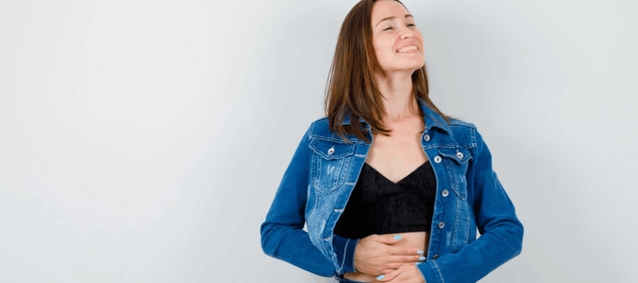 mulher feliz com as maos na barriga no tempo de digestão