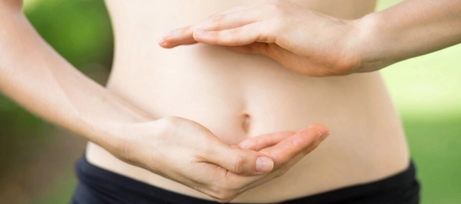 mulher saudável com close em suas mãos em frente à barriga