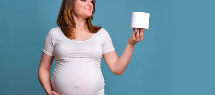 uma mulher grávida segurando um rolo de papel higiênico