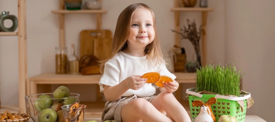 uma menina sentada em uma mesa com uma cesta de frutas