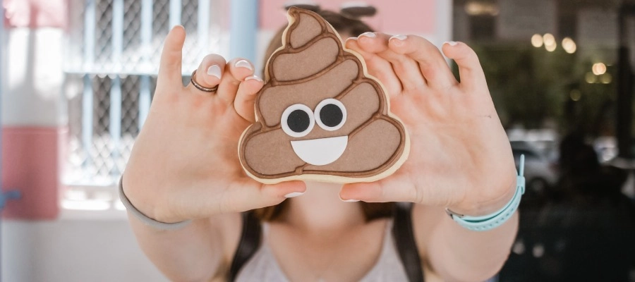 uma mulher segurando um cookie em forma de emoji poop