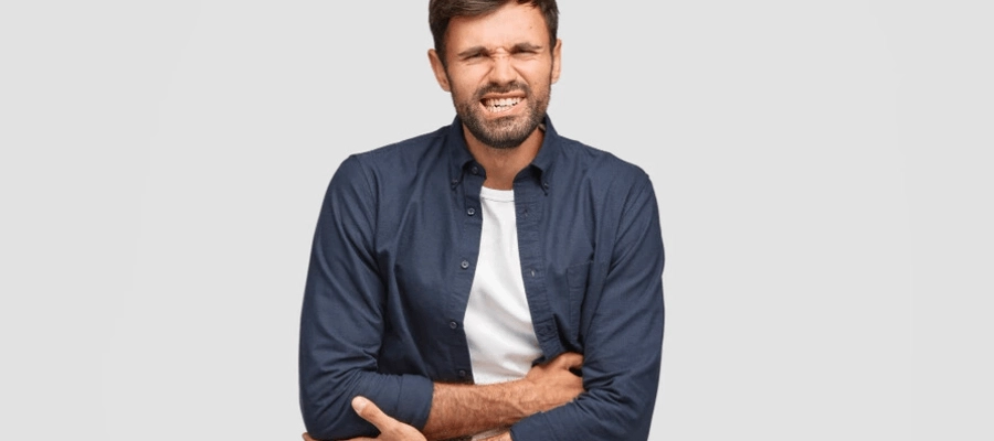 homem com camiseta branca e camisa aberta com as mãos na barriga e expressão de dor