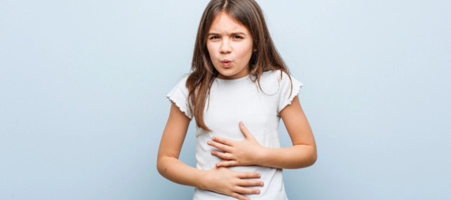 Menina com expressão preocupada segurando a barriga