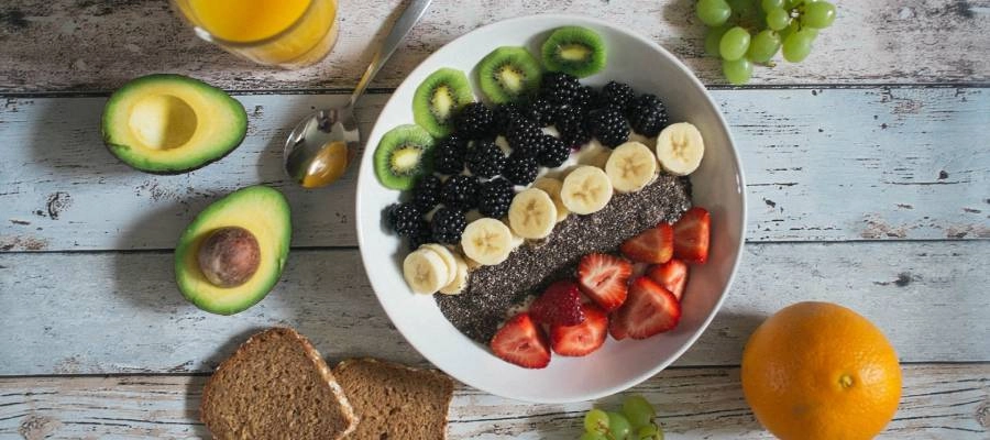 uma tigela de frutas, pão e suco de laranja