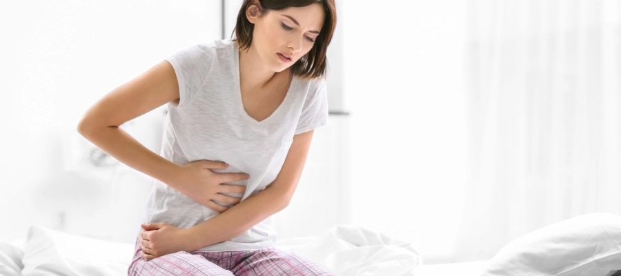 uma mulher sentada em uma cama com lençóis brancos