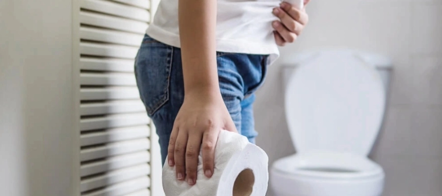 Homem na porta do banheiro segurando um rolo de papel higiênico