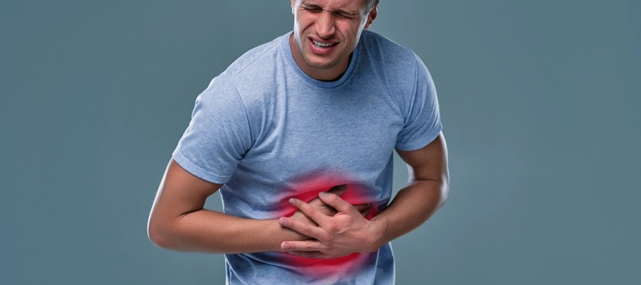 homem em fundo netro com dor e mão na barriga