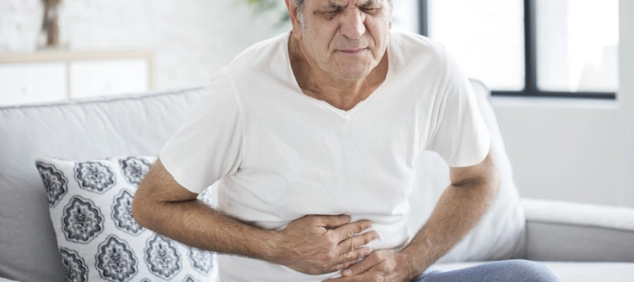 homem mais velho sentado com dor na barriga