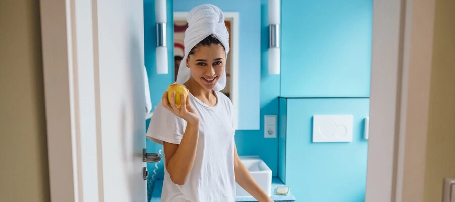 Mulher jovem no banheiro, segurando uma maçã para melhorar consistência das fezes.