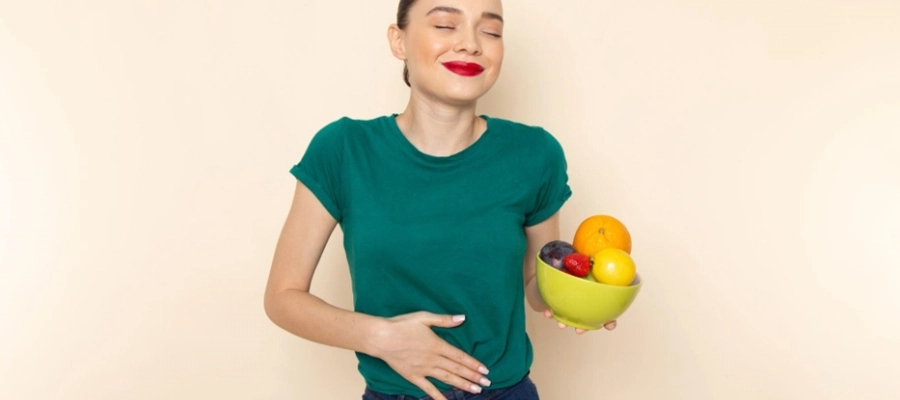 mulher de camisa verde segura tigela de frutas com a mão na barriga
