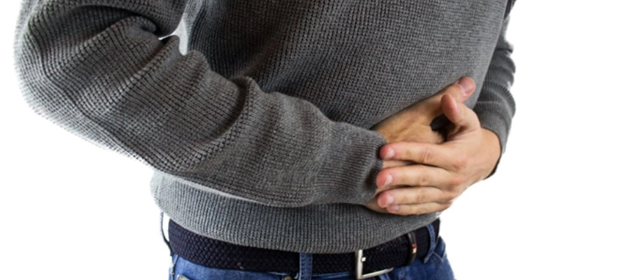um homem em um suéter cinza e jeans segura a barriga