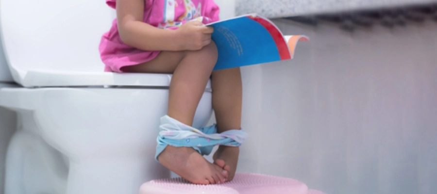 uma menina sentada em um assento de vaso sanitário
