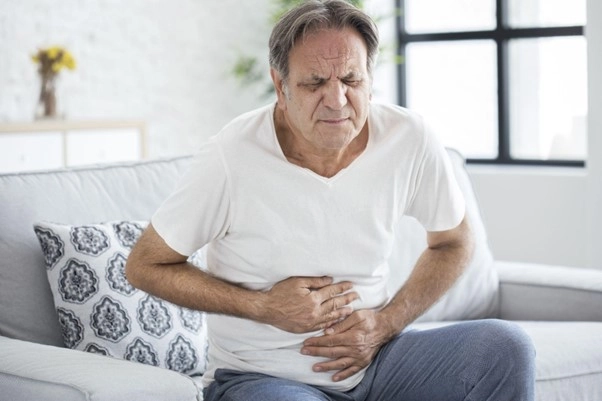 homem mais velho de camisa branca com as mãos na barriga