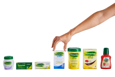 Imagem contendo todas as embalagens dos produtos de Tamarine, onde uma mão está pegando a embalagem  de Tamarine Probium bem no centro de todas.